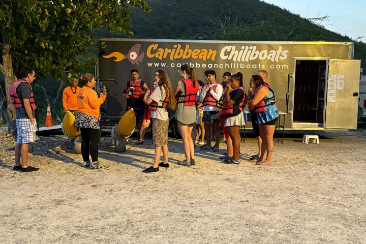 Group of people wearing life vests gather near a Caribbean Chillboats trailer.