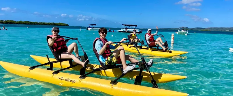 People on yellow water bikes in clear blue water under a bright blue sky.
